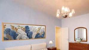A room with a large floral artwork on the wall, a chandelier, a bed, a dresser, and a mirror. - Apartment 'Residenza San Nicolò Treviso' with Private Terrace, Wi-Fi and Air Conditioning (Treviso)