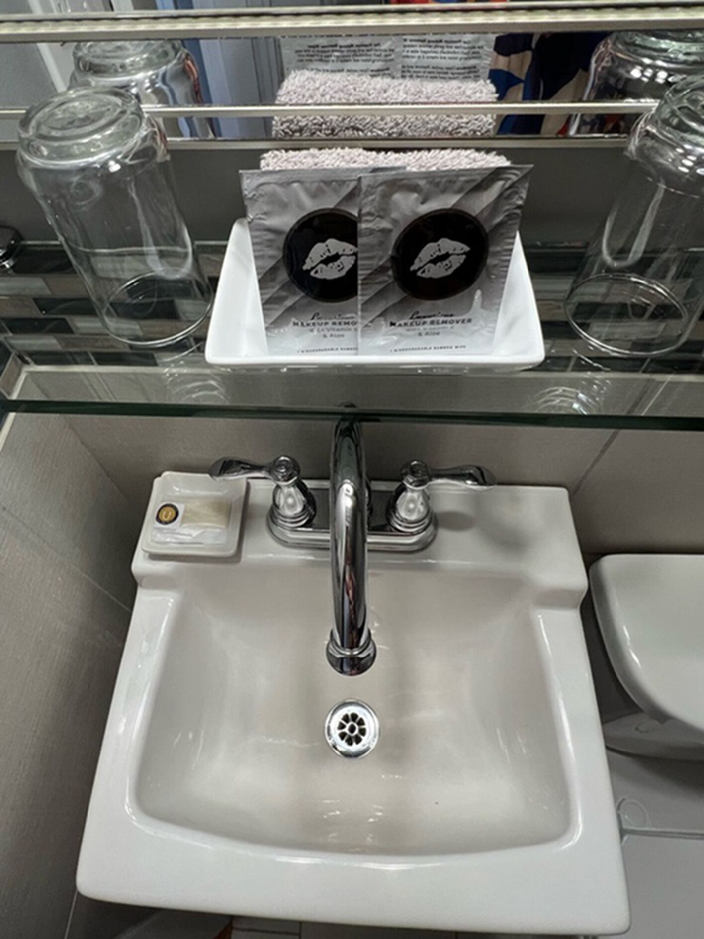 Ein Badezimmer mit Glasabtrennung, einem weißen Waschbecken und einem Spiegel darüber.