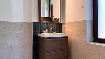 Une salle de bain moderne avec un meuble-lavabo, des carreaux foncés et un meuble en bois.