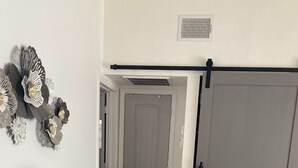 Un salón con sofás estampados, una lámpara de mesa, un adorno en la pared y una puerta corredera.