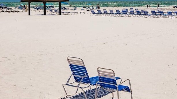 Una playa con un pabellón y sillas reclinables.