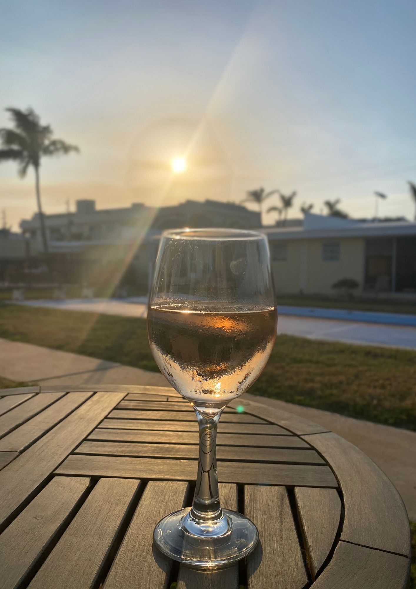 Ein Glas Wasser auf einem Holztisch, im Hintergrund ein Sonnenuntergang.