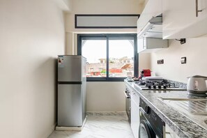 Une cuisine de taille réduite, équipée d’un réfrigérateur, d’une cuisinière et d’une fenêtre.