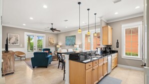 A spacious kitchen with a central island, wooden cabinets, and pendant lighting. - Private beach cottage + golf cart (Miramar Beach)