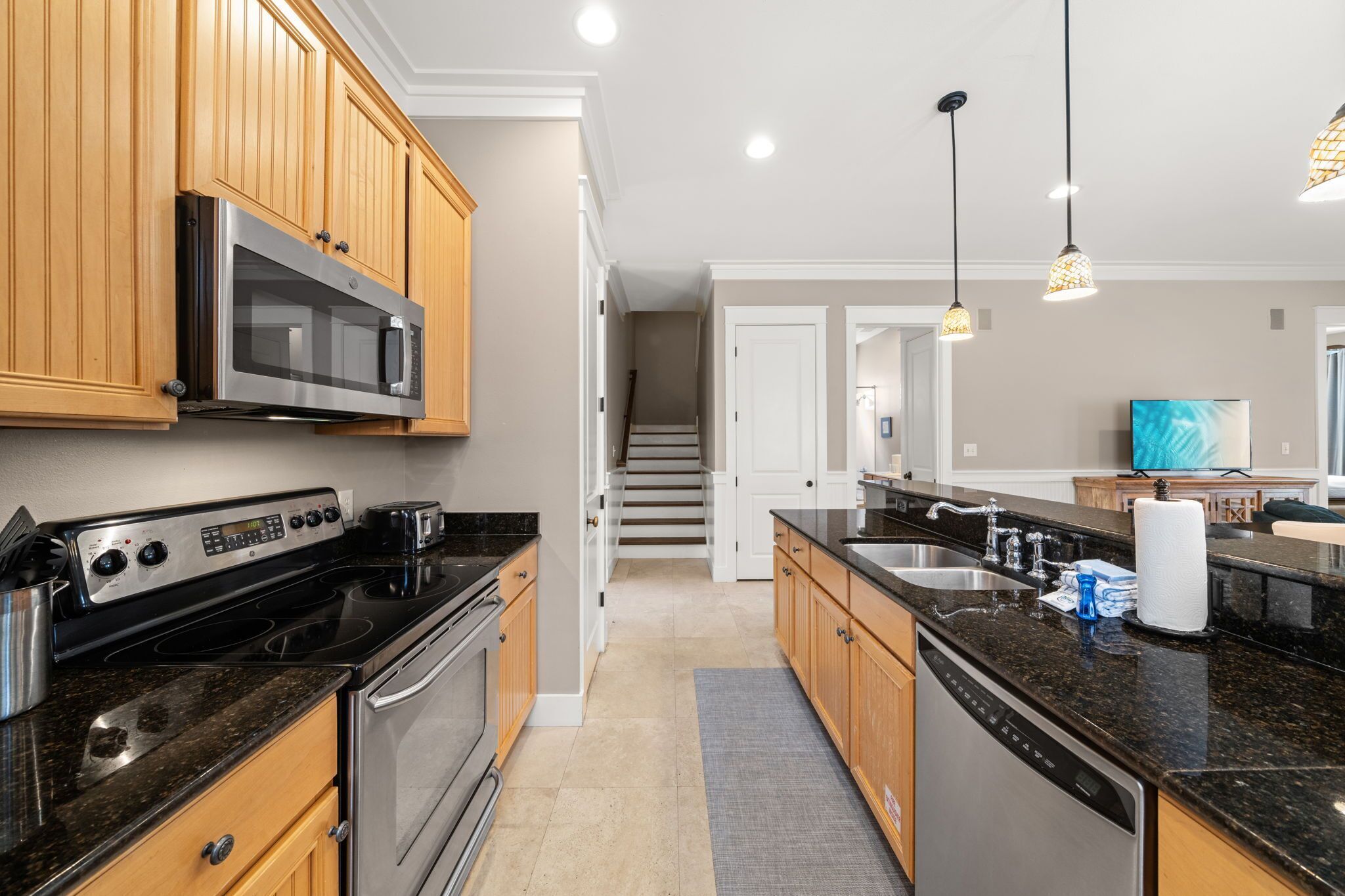 A modern kitchen with wooden cabinets, stainless steel appliances, and a granite countertop.