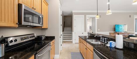A modern kitchen with wooden cabinets, stainless steel appliances, and a granite countertop.