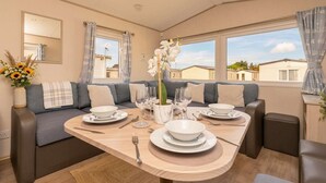 Un comedor con una mesa preparada para cuatro personas, un sofá y un ventanal con vistas a casas.