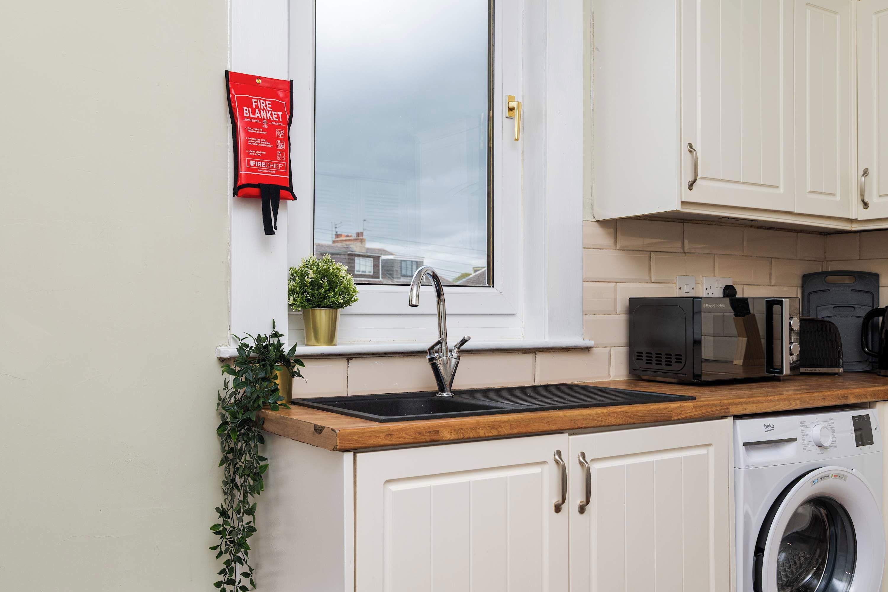A kitchen with a sink, a microwave, a coffee maker, and a washing machine.