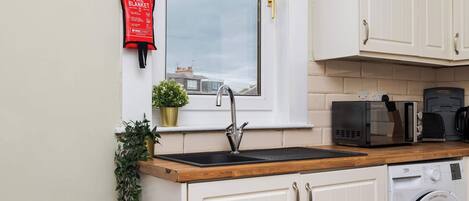 A kitchen with a sink, a microwave, a coffee maker, and a washing machine.