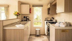 Une cuisine compacte équipée d’un évier, d’une cuisinière et d’une pancarte indiquant « Prête à accueillir les invités ».