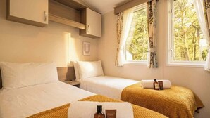 Une chambre d’hôtel avec deux lits, une fenêtre avec des rideaux, une table de chevet et une armoire.