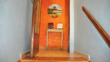 A staircase with a wooden handrail, a small table with a framed picture and a plaque, and a wall with a circular painting.