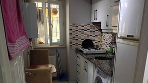 A compact kitchen with a washing machine, a window with blinds, and a radiator. - Room-standard Twin Bedroom (Istanbul)