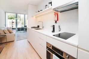 Una cocina moderna con armarios blancos, horno empotrado y placa de inducción negra.