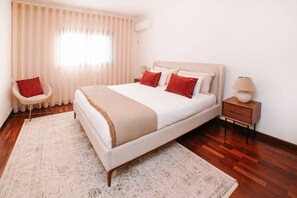 Une chambre à coucher avec un lit, une chaise, une table de chevet et une lampe.