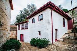 Ein weißes Gebäude mit rotem Zierstreifen, eine Steinmauer und ein Kopfsteinpflasterweg.