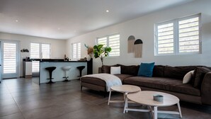 A spacious living area with a brown sofa, a coffee table, and a kitchen area with a bar stool. - Aqua Vista, Oceanview Villa with infinity pool Coral Estate close to the beach! (Sint Willibrordus)