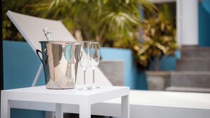 A white table with a silver bucket and two glasses on it, set against a backdrop of a blue chair and greenery. - Aqua Vista, Oceanview Villa with infinity pool Coral Estate close to the beach! (Sint Willibrordus)