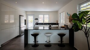 A modern kitchen with a central island, three bar stools, and a large potted plant. - Aqua Vista, Oceanview Villa with infinity pool Coral Estate close to the beach! (Sint Willibrordus)