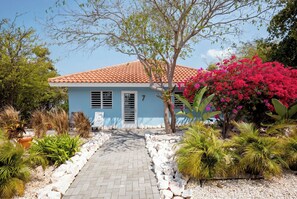 A house with a tiled roof, a pathway leading to the entrance, and various plants and trees around. - Aqua Vista, Oceanview Villa with infinity pool Coral Estate close to the beach! (Sint Willibrordus)