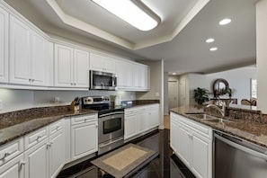 A modern kitchen with white cabinets, granite countertops, stainless steel appliances, and recessed ceiling lighting. - Margate Towers 1403 - Ocean views from Private Deck! (Myrtle Beach)