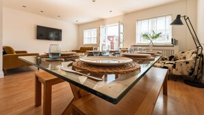 A modern dining area with a glass table, wooden chairs, and a sofa. - 3 The Yard (Swanage)