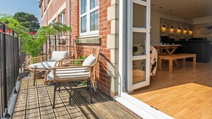A modern apartment with a patio, wicker furniture, a kitchen, and a sliding glass door. - 3 The Yard (Swanage)