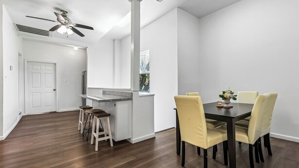 Cozinha moderna com área de refeições, piso de madeira e ventilador de teto.