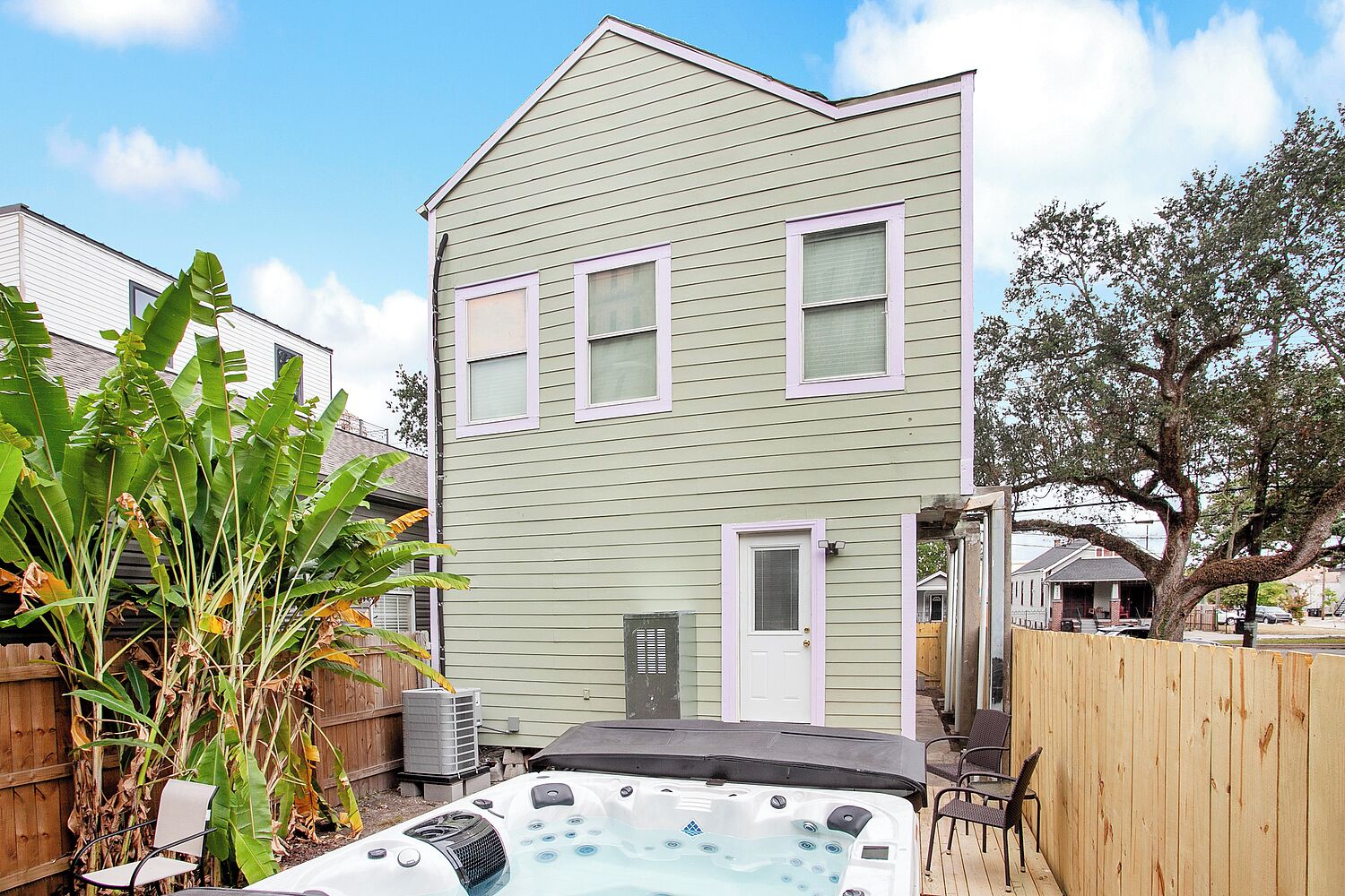 Una casa de dos pisos con un jacuzzi en el jardín trasero.