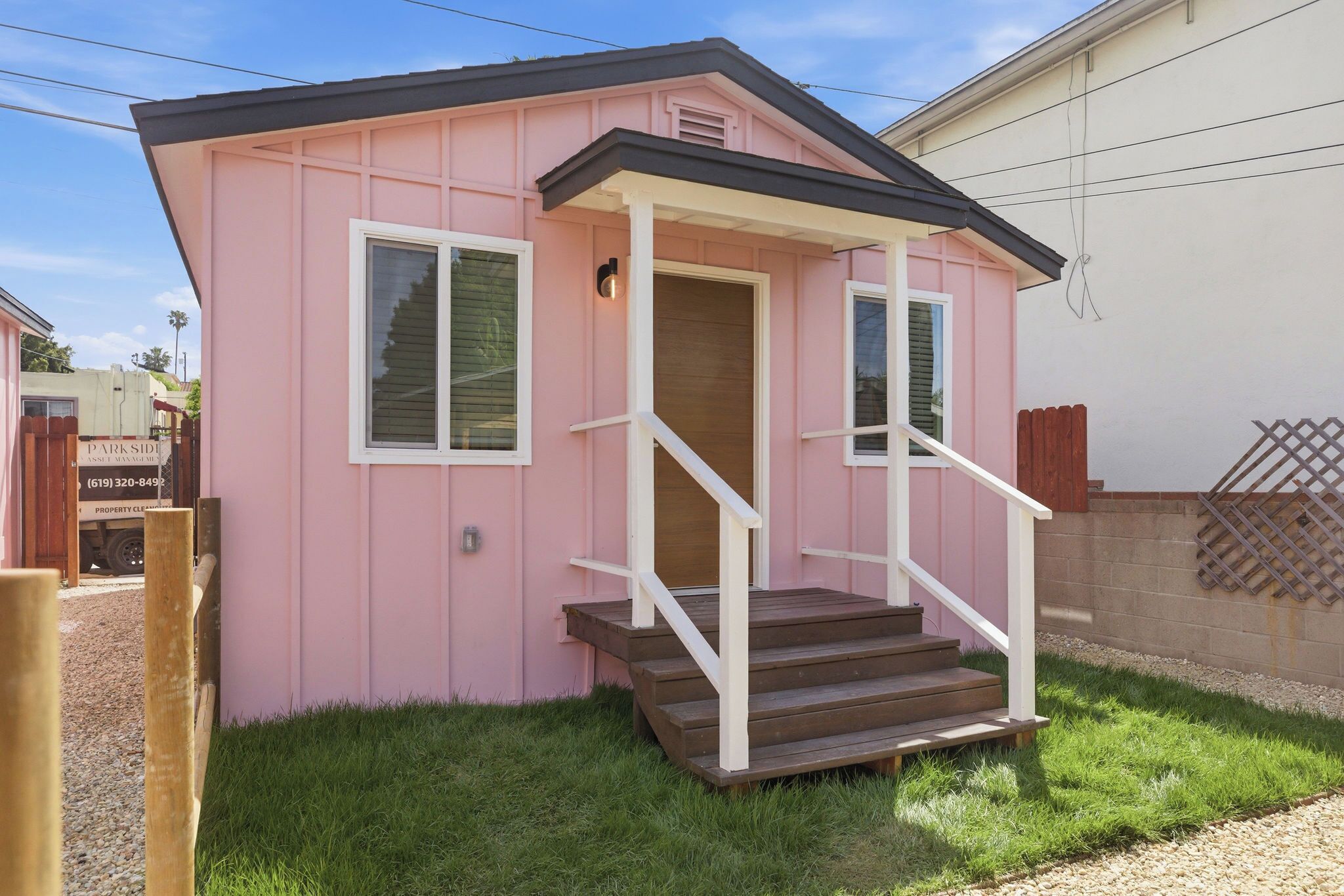A small pink house with a porch and steps leading to a door.