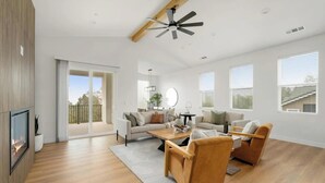 A spacious living room with a fireplace, a ceiling fan, and a large sliding glass door leading to an outdoor area. - Fabulous, brand new 3-bedrm house with views, high-speed internet, AC in Auburn. (Auburn)