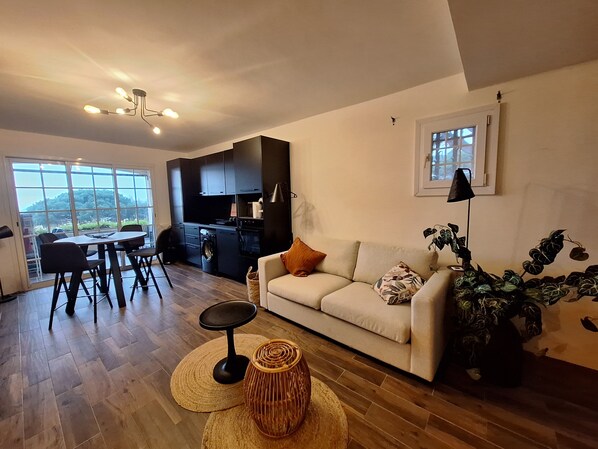 Ein modernes Wohnzimmer mit einer Couch, einem Esstisch und einer Küchenzeile.