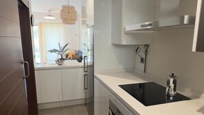 Une cuisine moderne dotée d’un grand îlot central, d’appareils électroménagers en acier inoxydable et offrant une vue sur l’espace de vie.