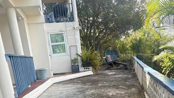 A concrete pathway leading to a building with a white facade, a blue railing, and potted plants.
