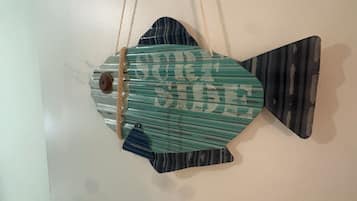 Een visvormige decoratie aan de muur, met de tekst 'SURE SIDE' en een deurklink links.