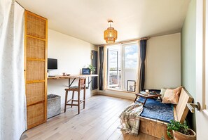 Ein Zimmer mit Schreibtisch, Stuhl und einem Bett mit blauer Bettdecke.