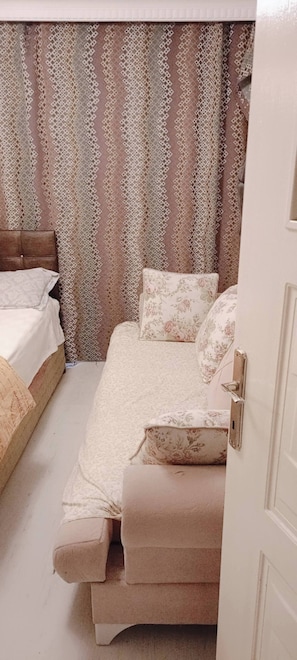 Ein Schlafzimmer mit einem Bett, einem Schlafsofa und einem gemusterten Vorhang.