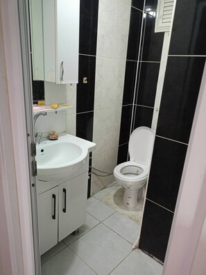 Ein Badezimmer mit weißem Waschbecken, Toilette und schwarz-weißen Fliesen.