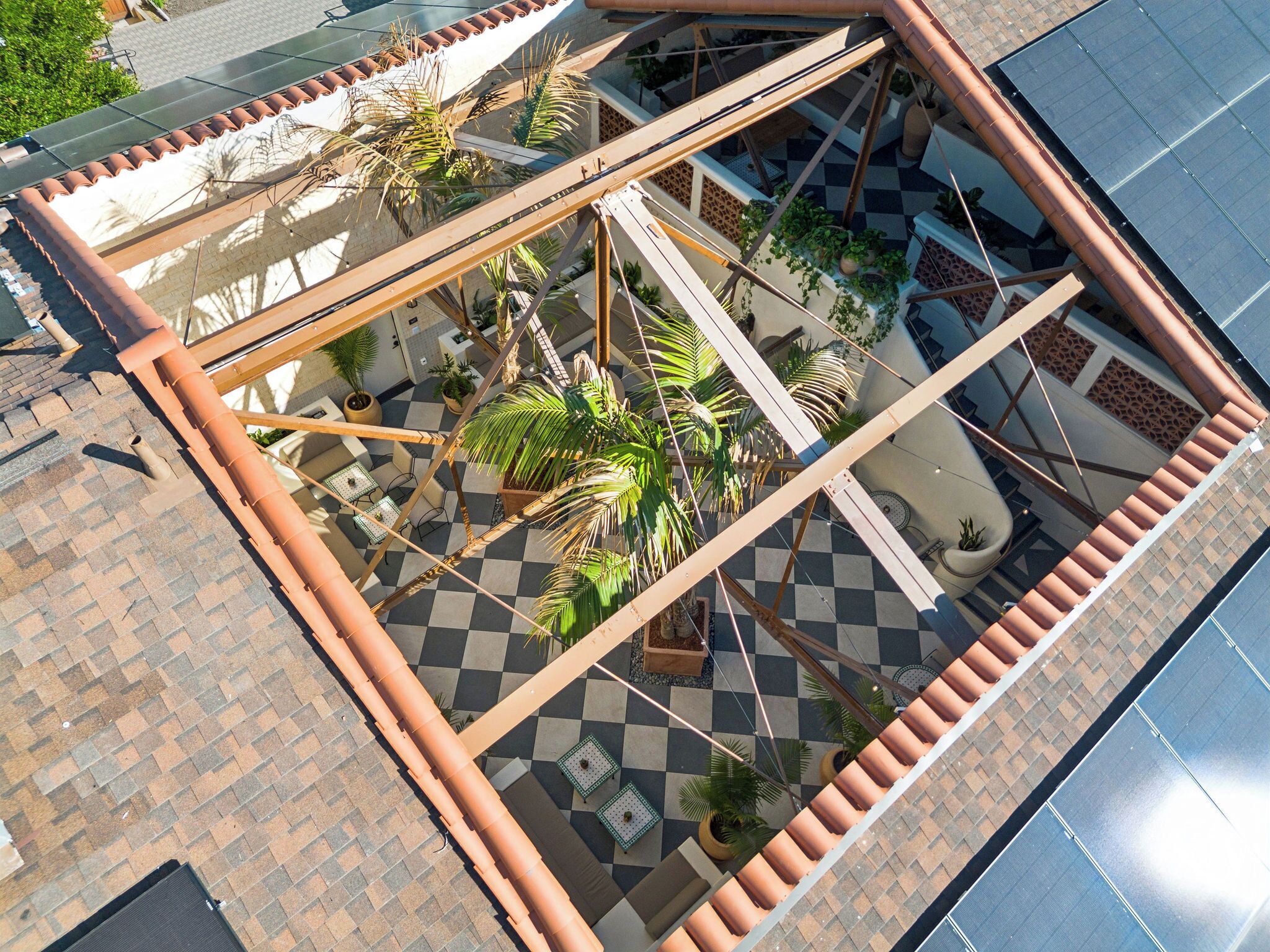 A rooftop terrace with a checkered floor, potted plants, and a pergola structure.
