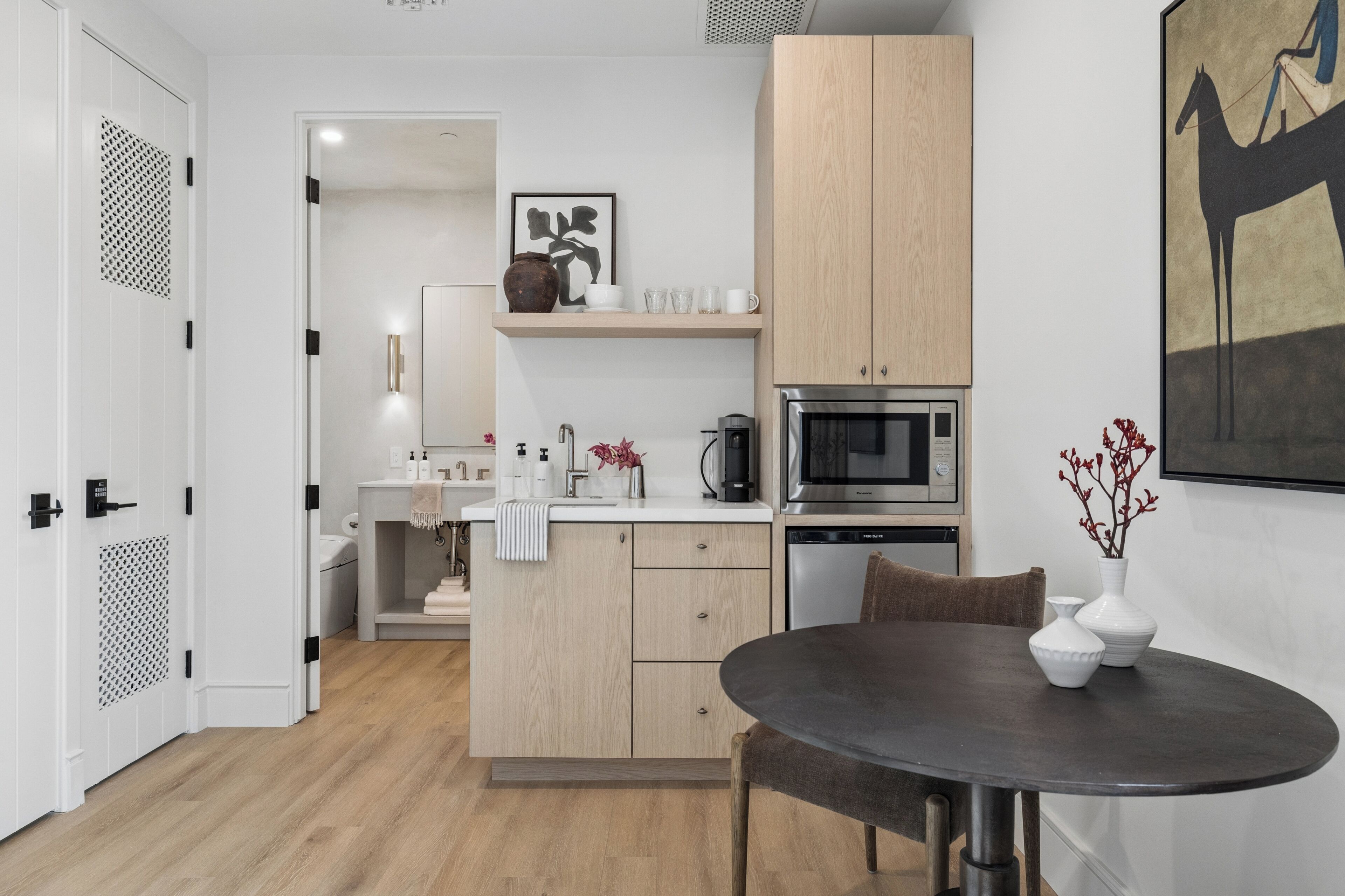 A modern kitchen with wooden cabinets, a microwave, and a dining area with a table and chairs.
