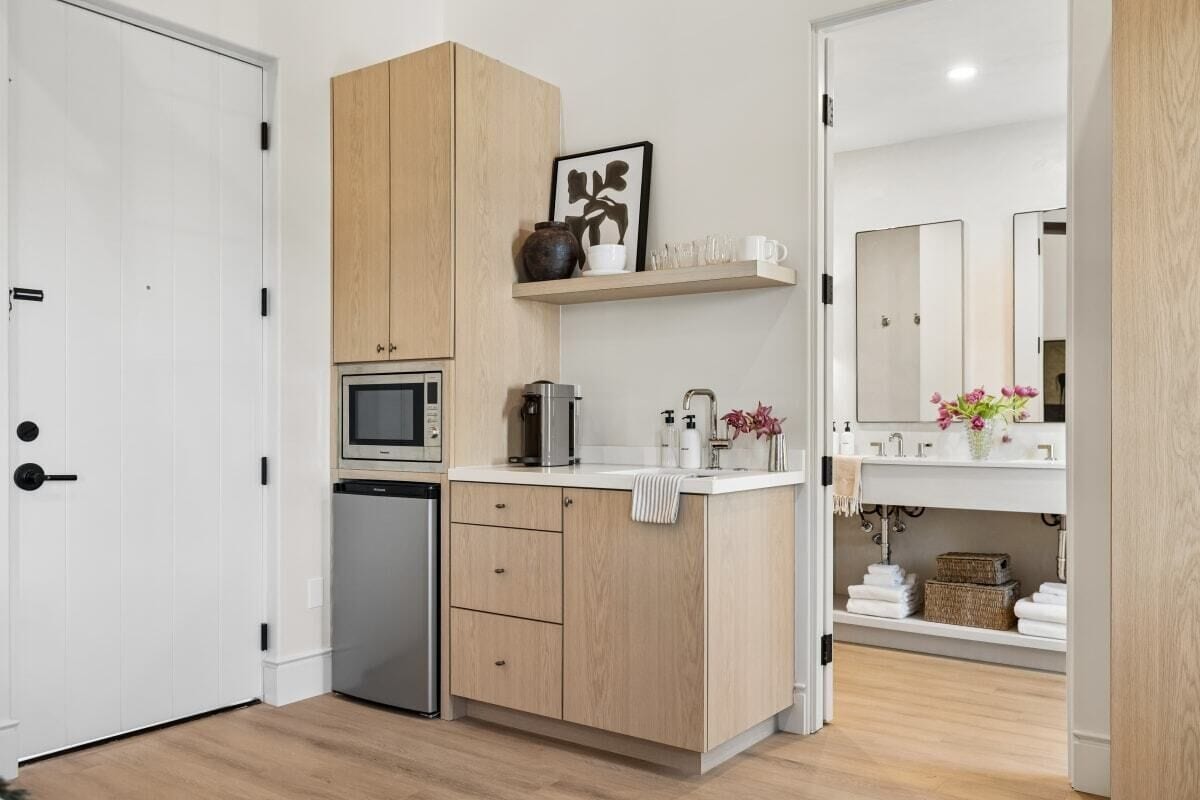 Una cocina compacta equipada con microondas, cafetera y un refrigerador pequeño.