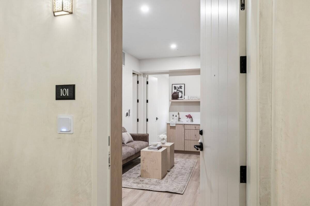 A hallway leading to a living area with a sofa, a coffee table, and a kitchen area with cabinets and a countertop.