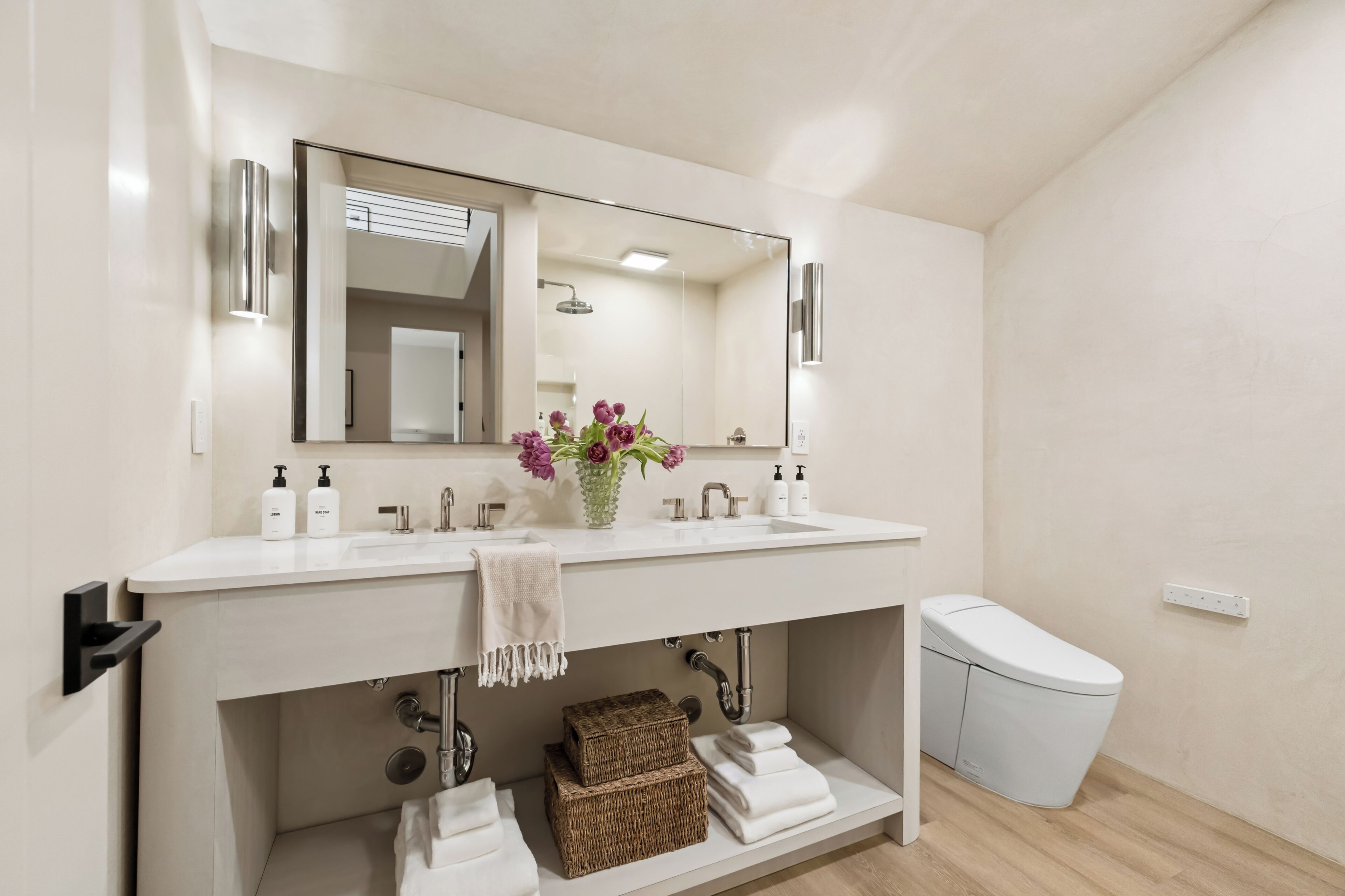 A modern bathroom with a white sink, mirror, and a toilet.