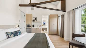 Une chambre d’hôtel moderne équipée d’un lit, d’une table à manger, d’une kitchenette et d’une grande fenêtre.