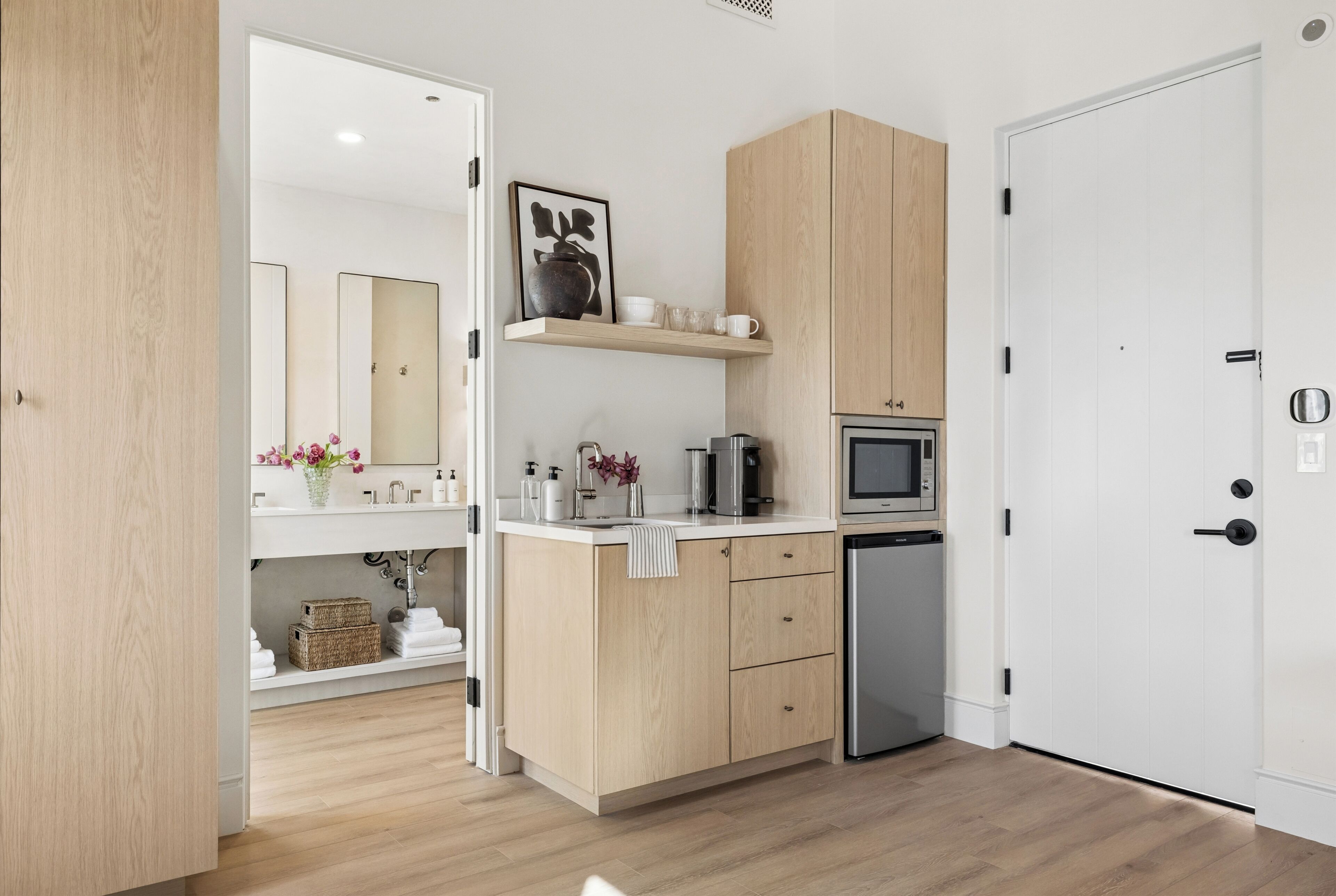 Una cocina compacta con armarios de madera, un microondas, una cafetera y un refrigerador pequeño.
