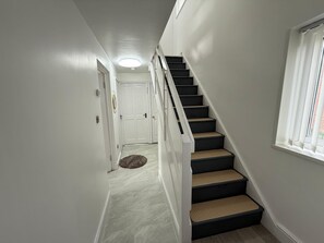 Una scala con corrimano, gradini rivestiti di moquette e una porta in cima.