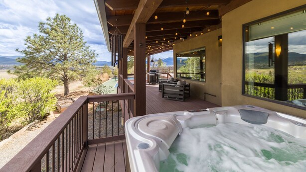 Un jacuzzi en una terraza de madera con vistas a montañas y árboles.