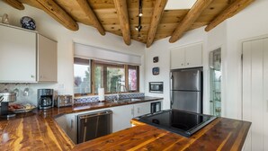 Una cocina con encimeras de madera, un refrigerador de acero inoxidable y un ventanal con vistas a árboles.