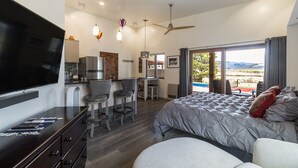 Un dormitorio moderno con una cama grande, un televisor, un escritorio y vistas al exterior.