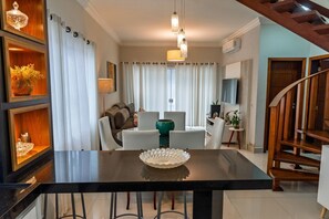 A modern kitchen with a black countertop, white chairs, and a dining table. - Casa c Churrasqueira a 300m da Praia de Massagua u (Caraguatatuba)